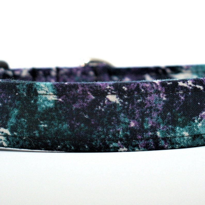 May include: A black dog collar with a purple and green tie-dye pattern.