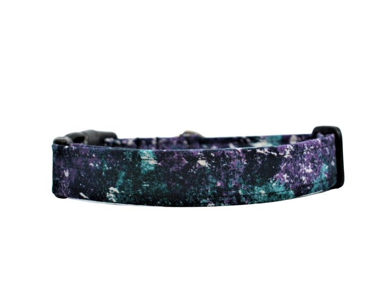 May include: A black, purple and teal patterned dog collar with a black plastic buckle.