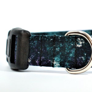 May include: A black and teal patterned dog collar with a black plastic buckle and a silver metal D-ring.