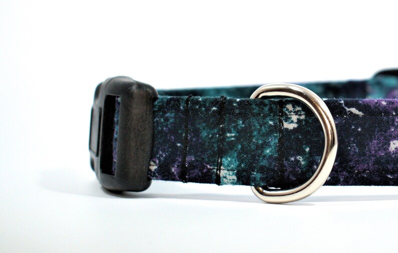 May include: A black and teal patterned dog collar with a black plastic buckle and a silver metal D-ring.