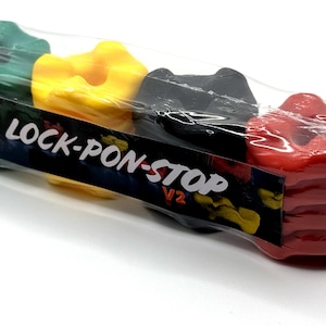Puede incluir: Cuatro agarres de escalada de plástico de colores: verde, amarillo, negro y rojo. Los agarres están empaquetados juntos y etiquetados como "Lock-Pon-Stop V2".