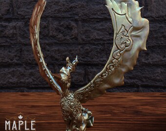 May include: A gold-colored, intricately detailed, 3D printed sculpture of a mythical creature with wings spread wide. The sculpture is on a wooden surface with a brick wall in the background. The sculpture has a detailed design with intricate patterns and textures.