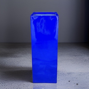 May include: A tall, square planter made of a glossy, blue material. The planter is empty and has a smooth surface.