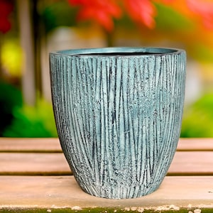 May include: A teal blue planter with a wood-grain texture. The planter is made of a durable material and has a rounded shape.