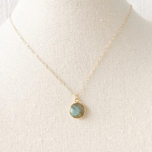 May include: A gold chain necklace with a round, iridescent green gemstone pendant.