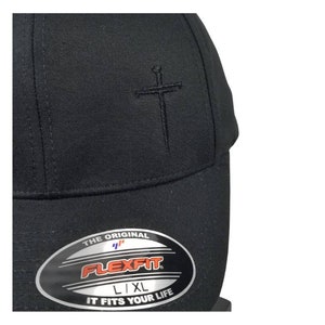 May include: Black baseball cap with a black embroidered sword and cross design. The cap has a Flexfit label with the text "The Original Flexfit L/XL It Fits Your Life."