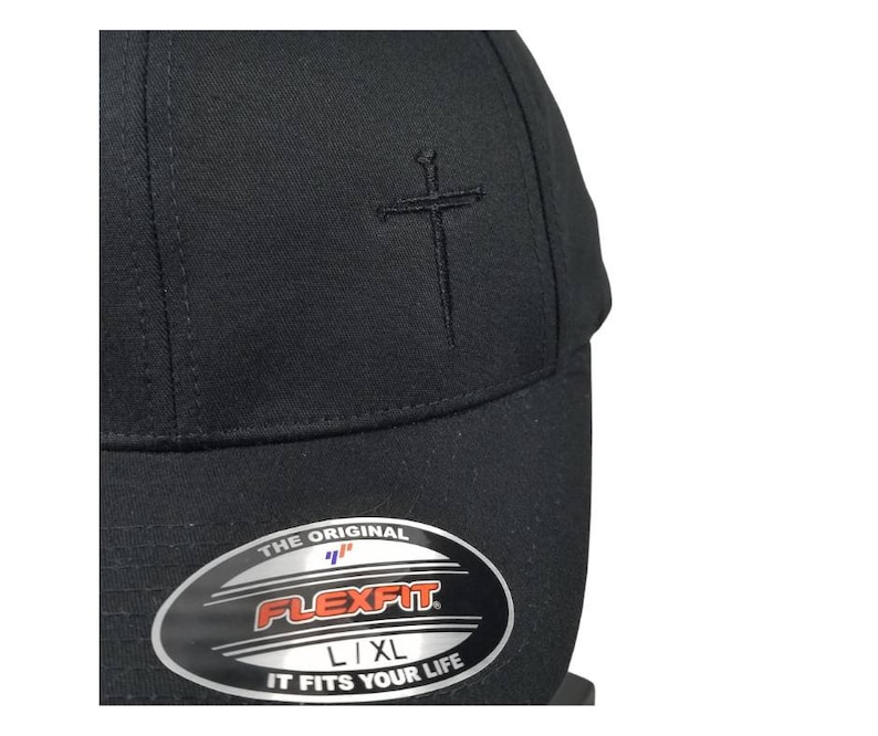 May include: Black baseball cap with a black embroidered sword and cross design. The cap has a Flexfit label with the text "The Original Flexfit L/XL It Fits Your Life."