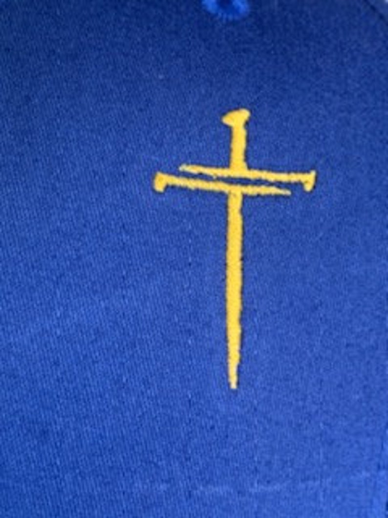 May include: A blue fabric patch with a yellow embroidered cross and nail.