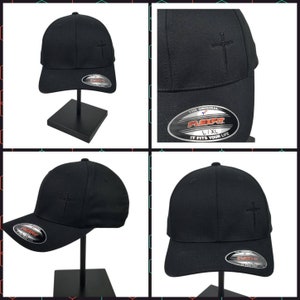 May include: Black baseball cap with a small cross embroidered on the front. The cap has a Flexfit label on the side with the text "The Original Flexfit L/XL It Fits Your Life".