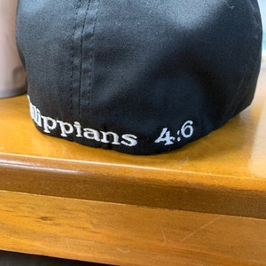 May include: Black baseball cap with white stitching and the text "Philippians 4:6" embroidered on the back.