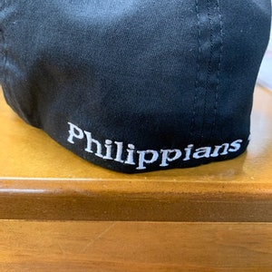 May include: Black baseball cap with white embroidery that reads "Philippians".