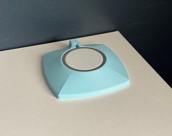 Op de afbeelding: Een lichtblauwe vierkante oplaadmat met een wit rond oplaadgebied in het midden.