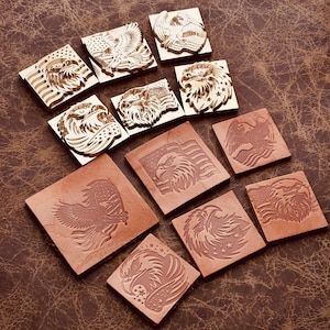 May include: A collection of square leather and wooden stamps featuring eagle designs. The stamps include images of eagles, American flags, and stars. The leather stamps are brown, and the wooden stamps are a light brown color.