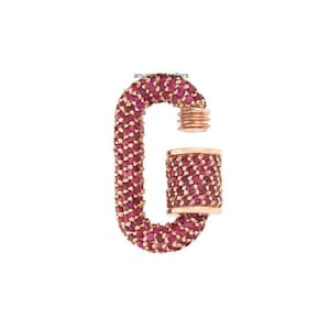 Pode incluir: Um fecho de ouro rosa com um design de pedras de rubi vermelhas. O fecho tem a forma de um mosquetão.