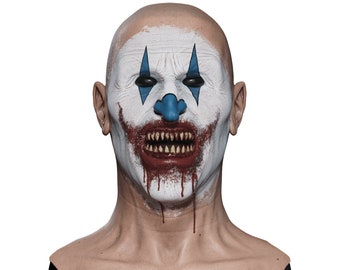May include: A close-up of a scary clown mask with white and blue makeup, a red nose, and a wide, toothy grin. The mask is dripping with fake blood.