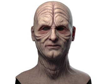 May include: A detailed bust of a fictional character with wrinkled skin and a serious expression. The bust is made of a light brown material and is displayed on a black base.