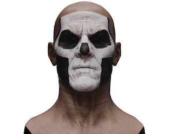 May include: A bald-headed man with a white and black skull painted on his face. The skull design is symmetrical and covers the forehead, eyes, nose, and mouth. The man is looking directly at the camera with a serious expression.