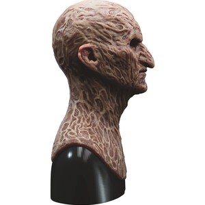 May include: A detailed, realistic, and disturbing latex mask of a burned human face. The mask is sculpted with intricate details of burned skin and is mounted on a black stand.