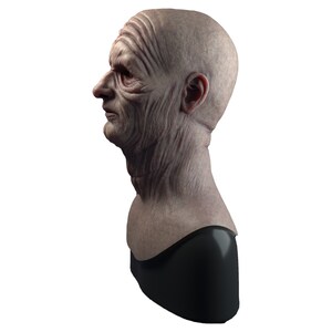 May include: A detailed bust sculpture of an elderly person's head and neck, with realistic wrinkles and skin texture. The bust is made of a light gray material and is mounted on a black base.