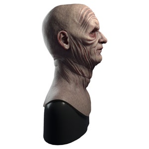 May include: A detailed bust sculpture of a person's head and neck, with a wrinkled, aged face and a black base.