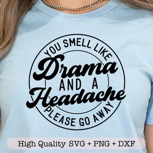 May include: A light blue t-shirt with a black circle graphic that says "You smell like drama and a headache please go away".