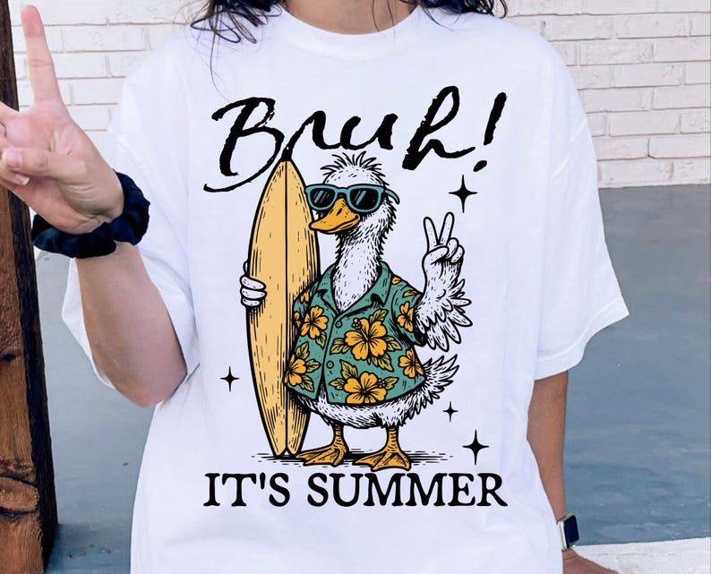 May include: White t-shirt with a cartoon duck wearing sunglasses and a floral shirt holding a surfboard. The text "Bruh! It's Summer" is printed on the shirt.