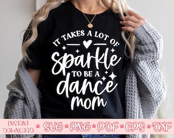 May include: Black t-shirt with white text that reads "It takes a lot of sparkle to be a dance mom". The text is surrounded by small stars and a heart.