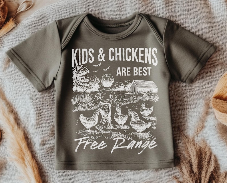 K&ouml;nnte beinhalten: Ein gr&uuml;nes T-Shirt mit kurzen &Auml;rmeln und einem wei&szlig;en Aufdruck eines Kindes und H&uuml;hnern. Der Aufdruck lautet "Kids & Chickens Are Best Free Range".
