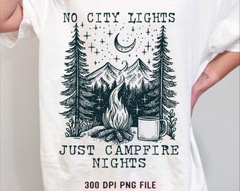Könnte beinhalten: Weißes T-Shirt mit einer Schwarz-Weiß-Grafik einer Lagerfeuerszene. Das Design umfasst ein Lagerfeuer, Berge, Bäume, einen Halbmond, Sterne und den Text "NO CITY LIGHTS JUST CAMPFIRE NIGHTS."