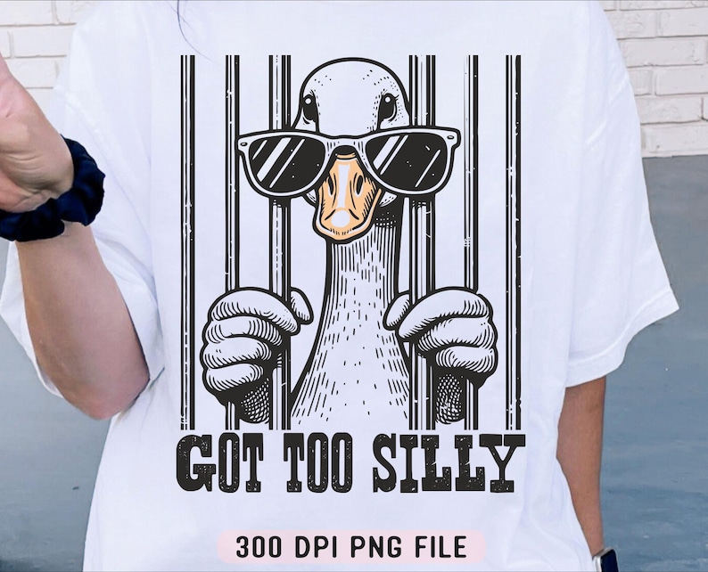 Pu&ograve; includere: Maglietta bianca con un'illustrazione di cartone animato di un'oca che indossa occhiali da sole e dietro le sbarre. Il testo "Got Too Silly" &egrave; stampato sotto l'immagine. Il testo "300 DPI PNG File" &egrave; stampato sul fondo della maglietta.