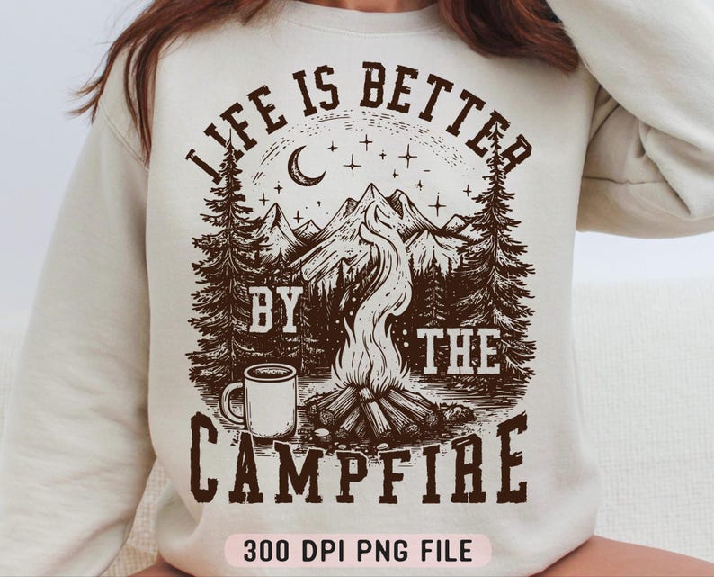 Puede incluir: Sudadera color crema con un gr&aacute;fico marr&oacute;n de una escena de fogata. El dise&ntilde;o incluye una fogata, monta&ntilde;as, &aacute;rboles, una luna creciente, estrellas y el texto "LIFE IS BETTER BY THE CAMPFIRE". Tambi&eacute;n se incluye una taza.