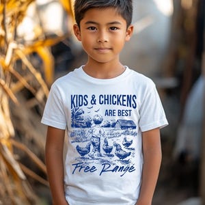 K&ouml;nnte beinhalten: Wei&szlig;es T-Shirt mit einer blauen Grafik eines Kindes und H&uuml;hnern. Die Grafik lautet "Kids & Chickens Are Best Free Range".