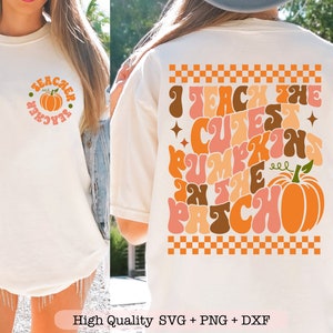 May include: White t-shirt with a pumpkin design and the text "Teacher" in a circle on the front. The back of the shirt has a checkered pattern and the text "I teach the cutest pumpkins in the patch" in a retro font.