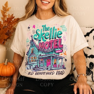 K&ouml;nnte beinhalten: Cremefarbenes T-Shirt mit einer farbenfrohen Illustration von "The Skellie Motel" mit einem gruseligen Hausdesign, Text und den Worten "Old Graveyard Road". Das Design umfasst T&uuml;rkis-, Rosa- und Lilat&ouml;ne.