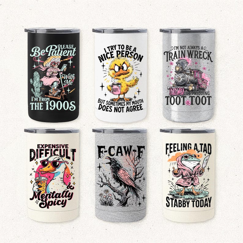 May include: Six stainless steel travel mugs with humorous illustrations and text. Designs include a woman with a cactus, a chick with a coffee cup, a train, a duck with sunglasses, a raven, and a frog with a knife. Each mug has a different design.