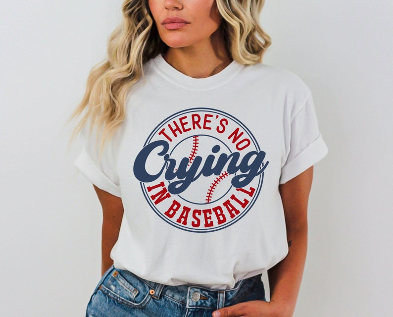 May include: White t-shirt with a blue and red baseball graphic and the text "There's No Crying In Baseball".