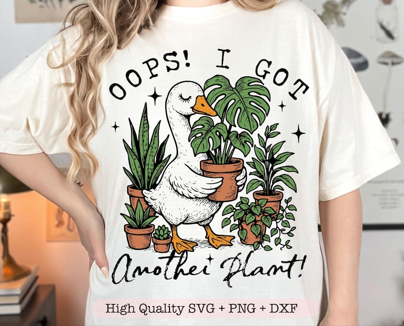 May include: A white t-shirt with a graphic of a goose holding a potted plant. The text "Oops! I got another plant!" is printed on the shirt.  High Quality SVG + PNG + DXF is printed at the bottom of the shirt.