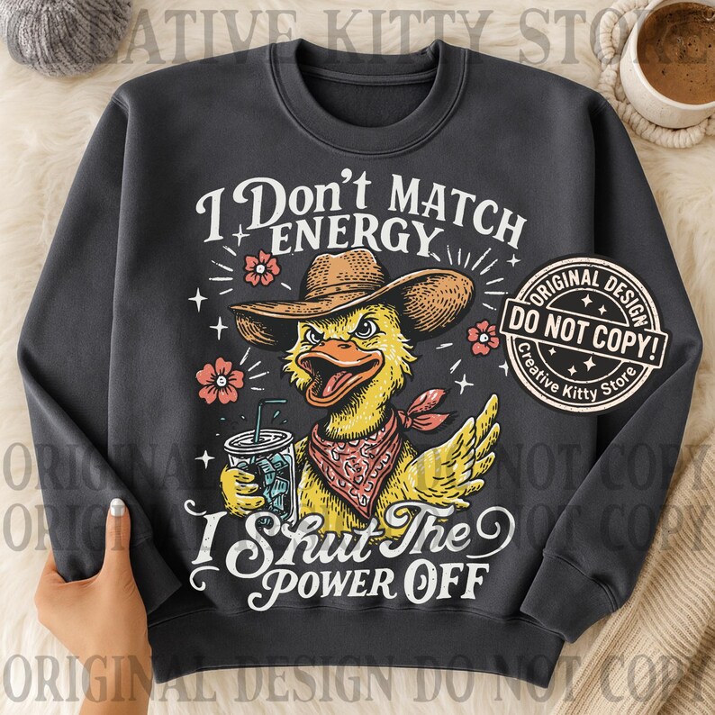 May include: Dark gray sweatshirt with a graphic of a yellow duck wearing a cowboy hat and bandana, holding a drink. Text reads "I Don't Match Energy, I Shut The Power Off." Features a "Do Not Copy" design.