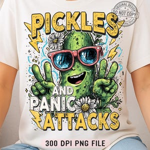 May include: White t-shirt featuring a cartoon pickle wearing sunglasses and making a peace sign. The text "PICKLES AND PANIC ATTACKS" is in yellow, with lightning bolt accents. The design includes daisies and the text "300 DPI PNG FILE".