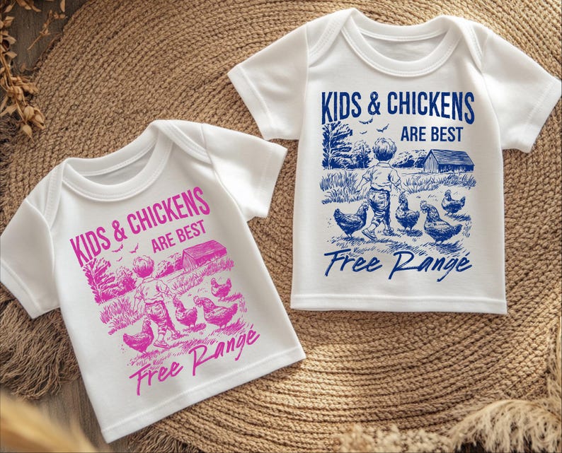 K&ouml;nnte beinhalten: Zwei wei&szlig;e T-Shirts mit einem blauen und rosa grafischen Aufdruck eines Kindes, das mit H&uuml;hnern geht. Der Text auf den Shirts lautet "Kids & Chickens Are Best Free Range".