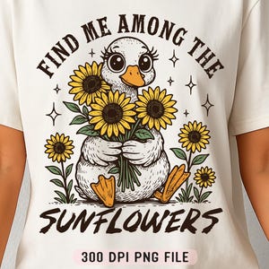 May include: A white t-shirt with a graphic of a duck surrounded by sunflowers. The text "Find me among the sunflowers" is printed above the graphic and "300 DPI PNG FILE" is printed below the graphic.