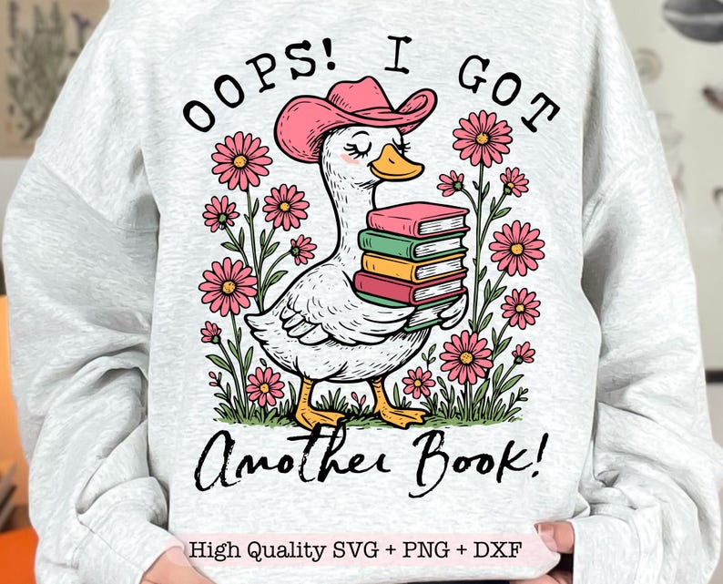 May include: A white duck with a pink cowboy hat is holding a stack of books. The duck is surrounded by pink flowers and the text "Oops! I got another book!" is written above the duck. The text "High Quality SVG + PNG + DXF" is written below the duck.