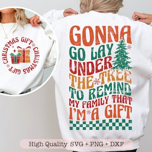 May include: White sweatshirt with a distressed red, green, and yellow graphic that says "Gonna go lay under the tree to remind my family that I'm a gift".