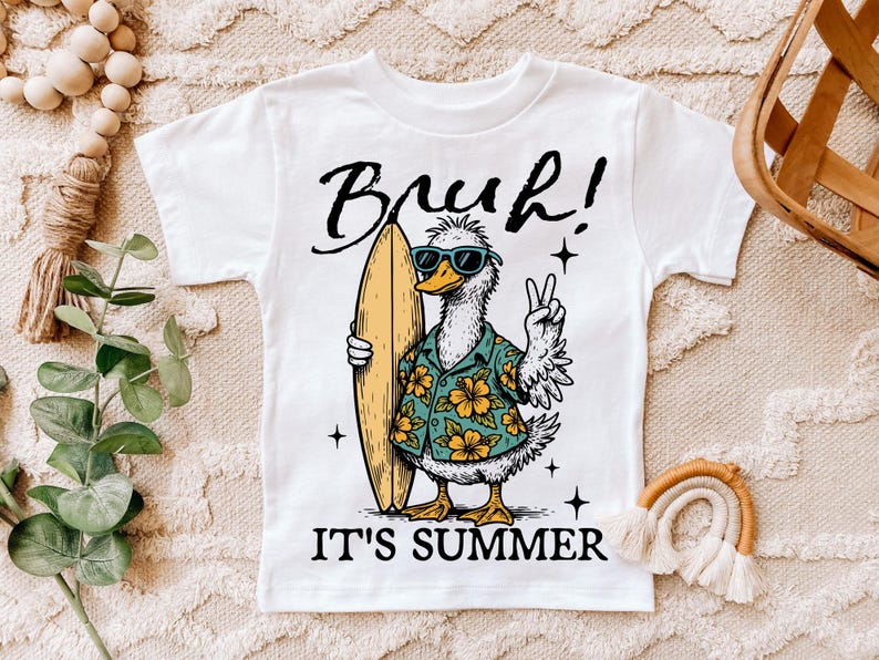 May include: White t-shirt with a cartoon duck wearing sunglasses and a floral shirt holding a surfboard. The text "Bruh! It's Summer" is printed on the shirt.