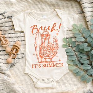 May include: A white baby onesie with an orange graphic of a cartoon bird wearing sunglasses and a floral shirt, holding a surfboard. The text "Bruh! It's Summer" is printed below the bird.