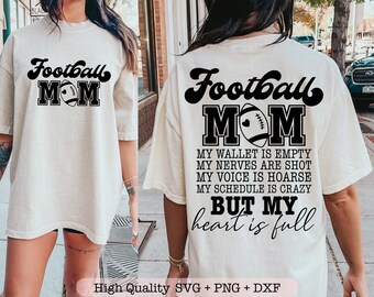 May include: A white t-shirt with black text that reads "Football Mom". The text is in a retro font and includes a football graphic. The text below the graphic reads "My wallet is empty, my nerves are shot, my voice is hoarse, my schedule is crazy, but my heart is full."