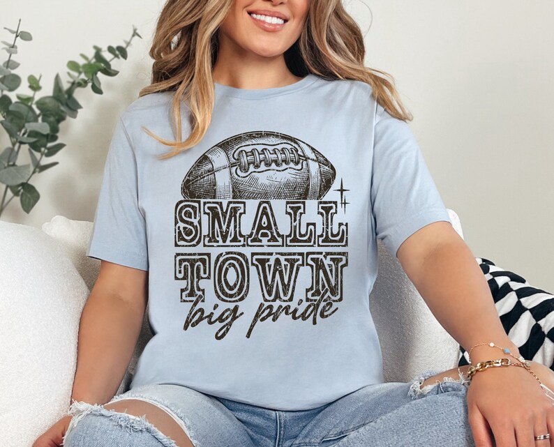 May include: A light blue t-shirt with a vintage-style football graphic and the text "SMALL TOWN big pride".
