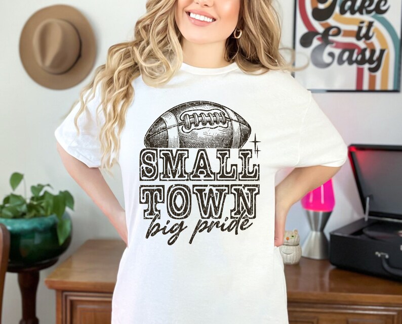 May include: White t-shirt with a black and white illustration of a football and the text "Small Town Big Pride".