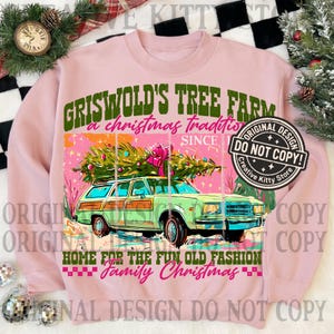 May include: Pink sweatshirt with a graphic of a green station wagon carrying a Christmas tree. Text reads "Griswold's Tree Farm, a Christmas tradition, Home for the fun old fashion family Christmas."