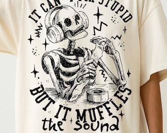 Peut inclure: T-shirt crème avec un graphisme noir d'un squelette portant un casque et utilisant du ruban adhésif. Le texte dit "IT CAN'T FIX STUPID BUT IT MUFFLES the SOUND." En dessous, "300 DPI PNG FILE."